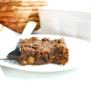 A pumpkin protein brownie on a white plate with a fork next to it.