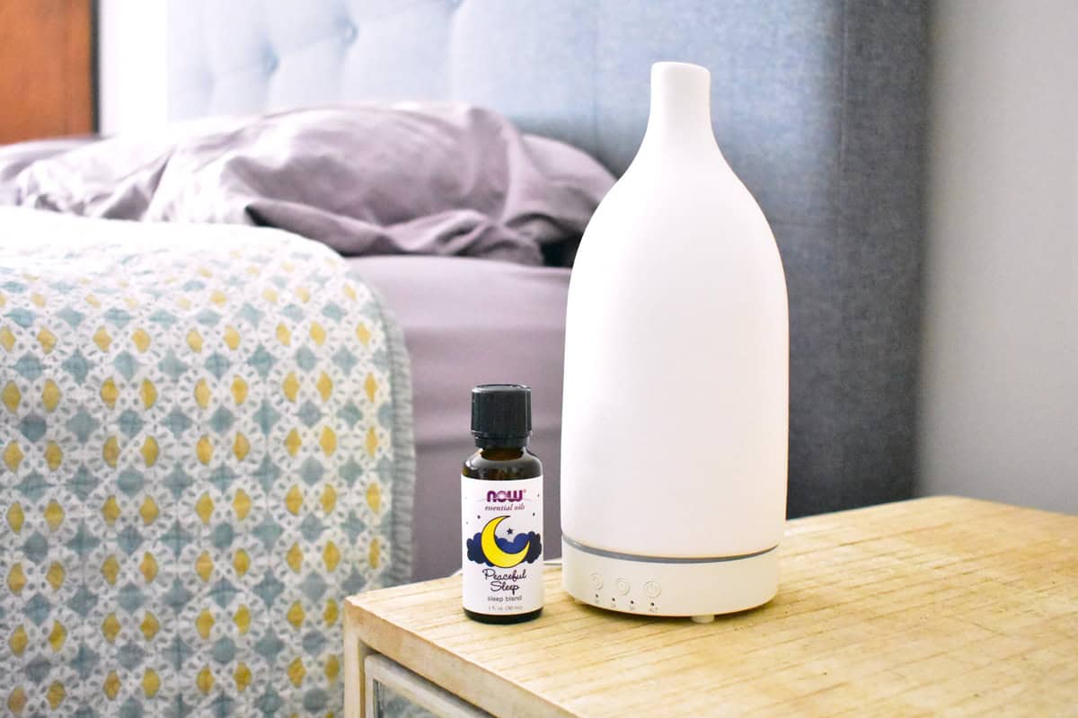 An essential oil diffuser next to a bed.