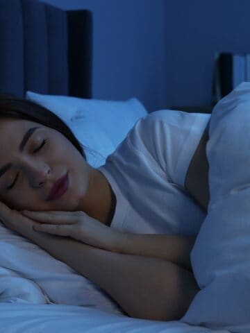 A woman sleeping in a bed at night.