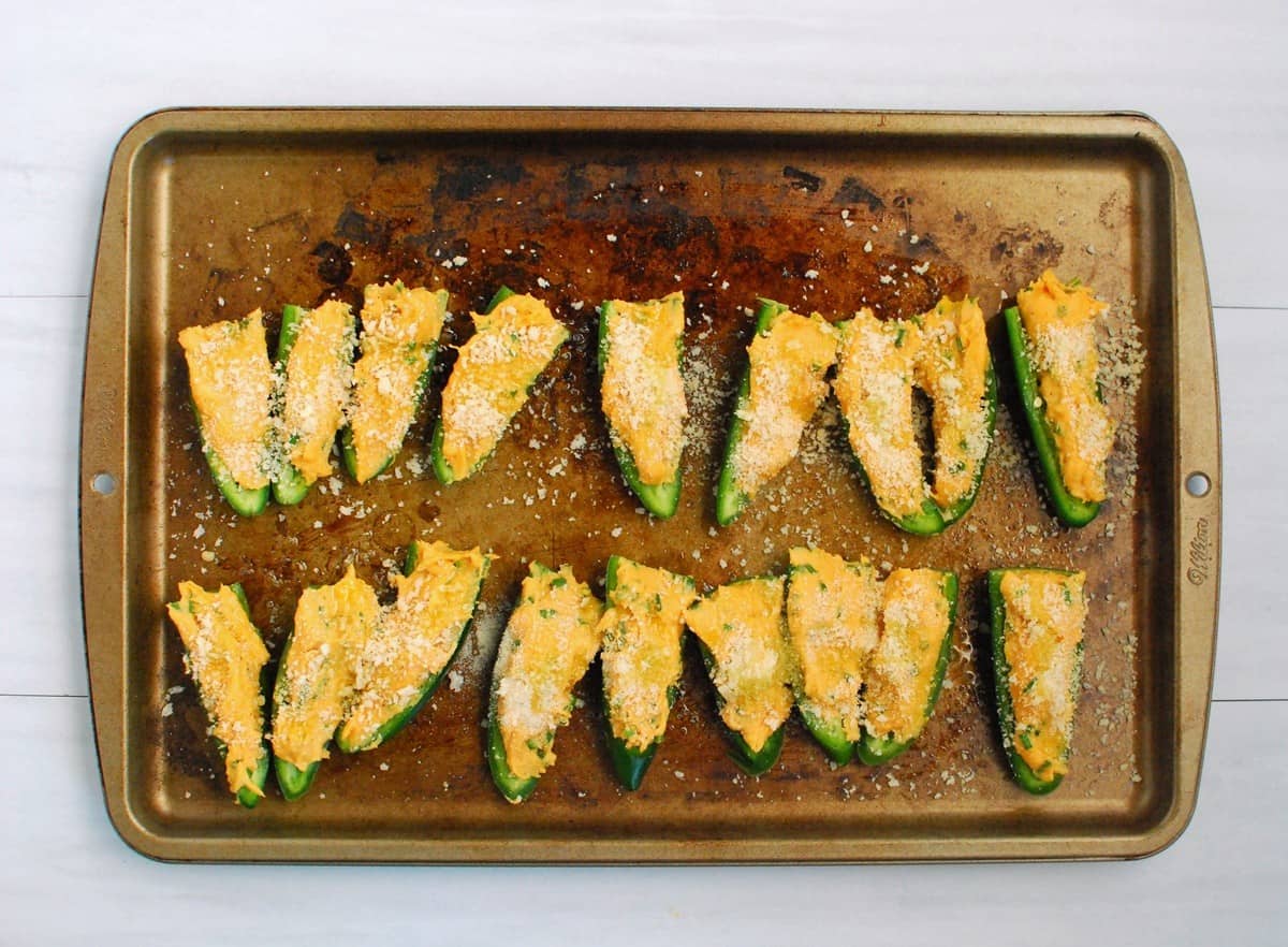 Uncooked jalapeno poppers on a baking sheet.
