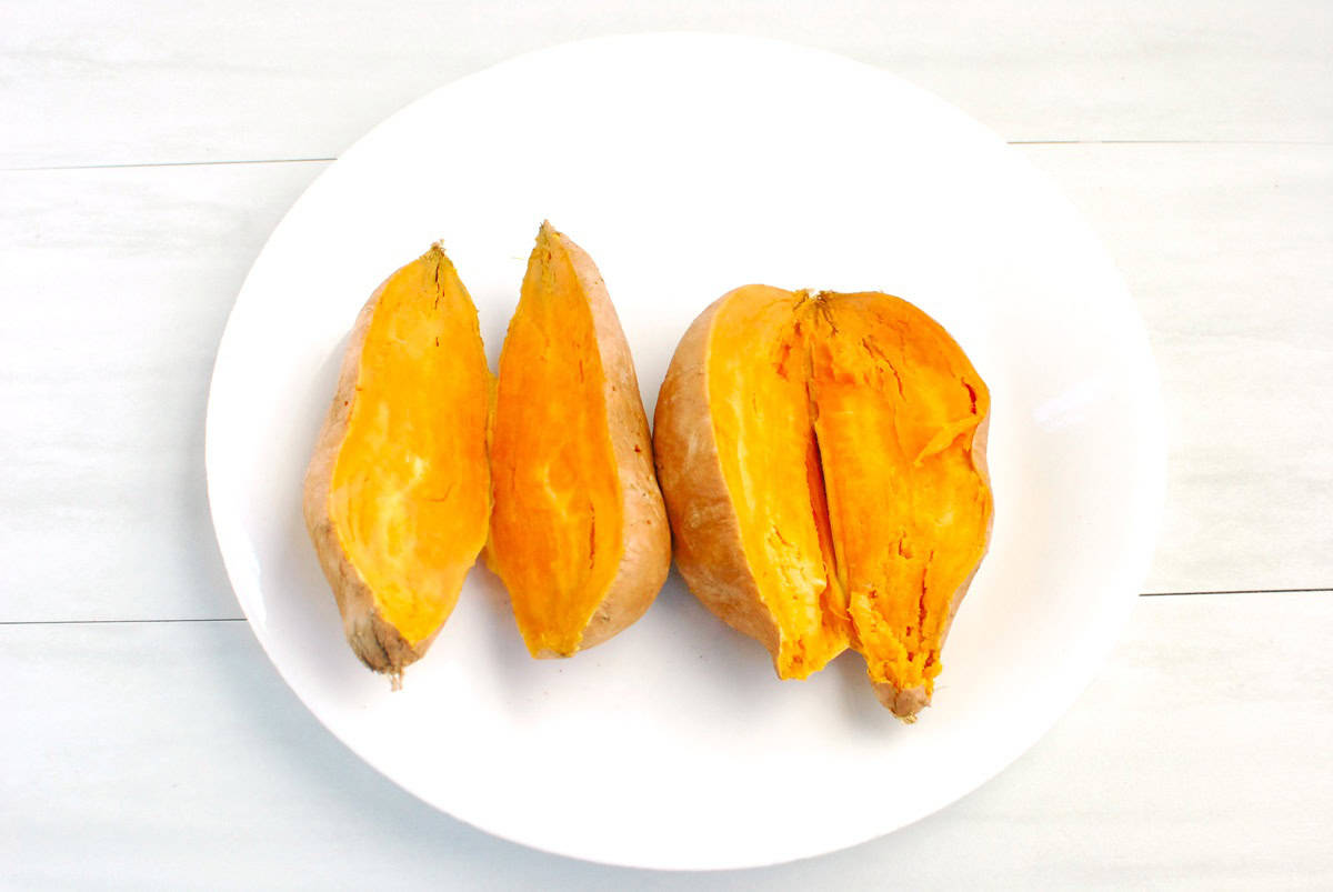 Sweetpotatoes on a plate cut in half after cooking in the microwave.