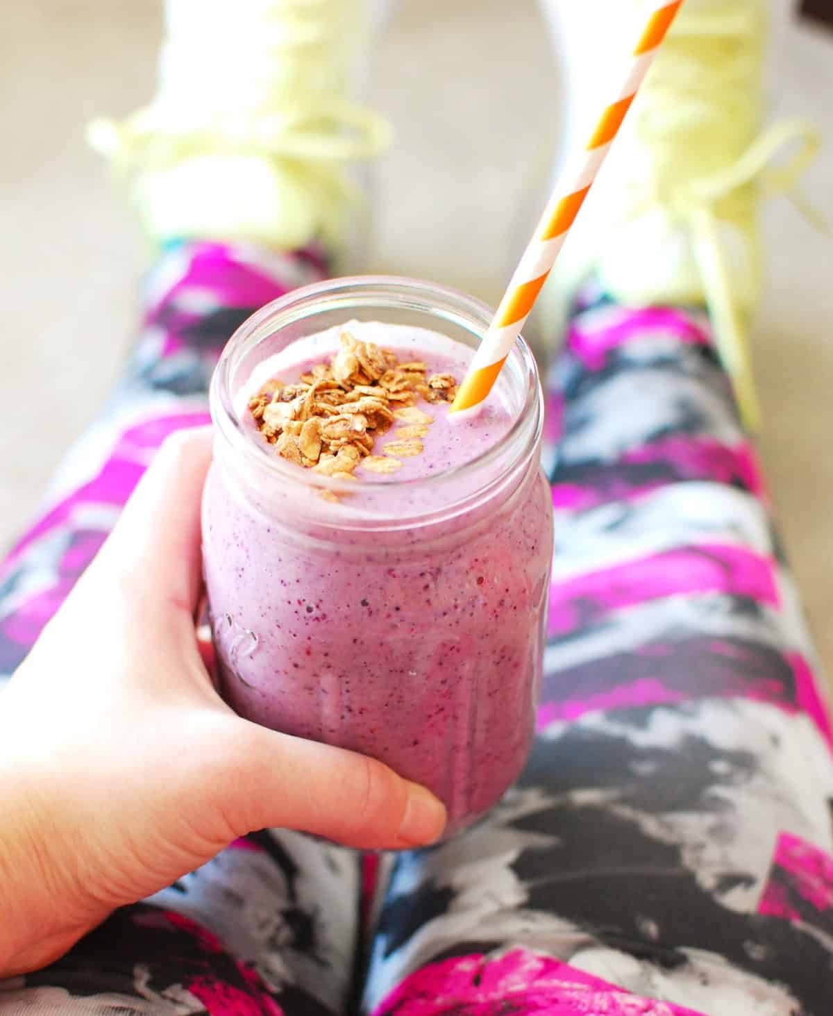 A woman holding a smoothie after a workout.