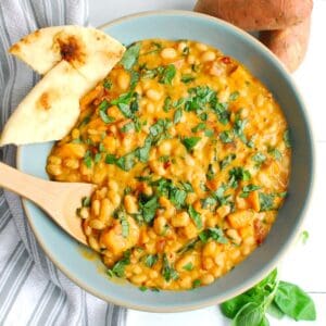 An overhead shot of a serving bowl filled with marry me beans and sweetpotatoes.