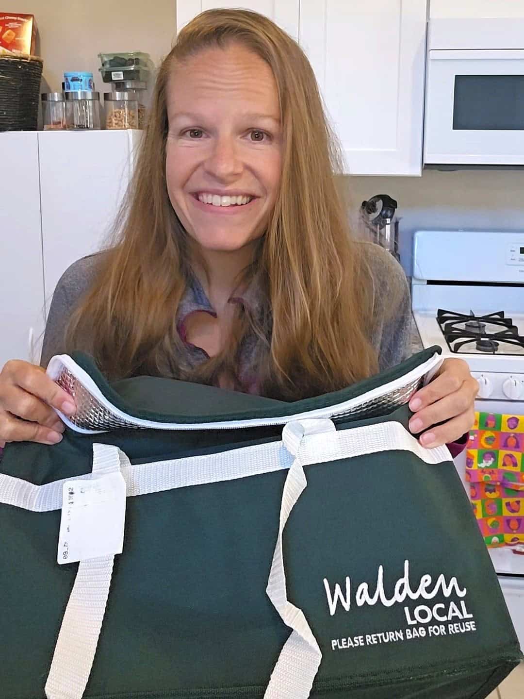 A woman holding a Walden Local bag of meat.