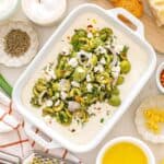 A dish filled with whipped feta dip with olives, garnished with a little extra feta.