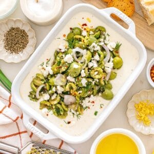 A dish filled with whipped feta dip with olives, garnished with a little extra feta.