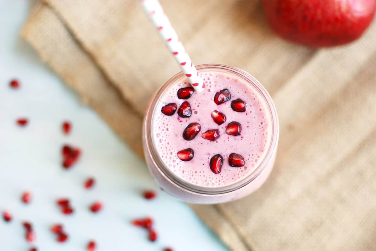 An overhead shot of a pomegranate cranberry smoothie garnished with pomegranate arils.