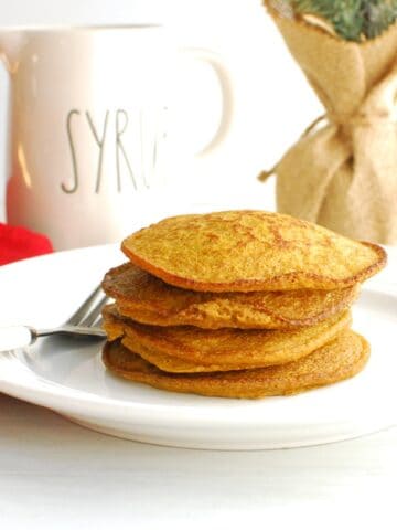 A stack of gingerbread pumpkin pancakes on a white plate.