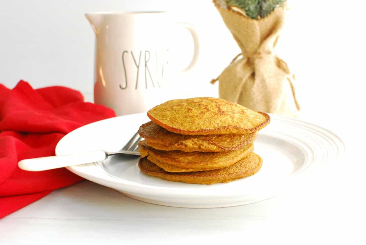 A stack of gingerbread pumpkin pancakes on a white plate.