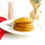 A stack of four gingerbread pumpkin pancakes on a plate.