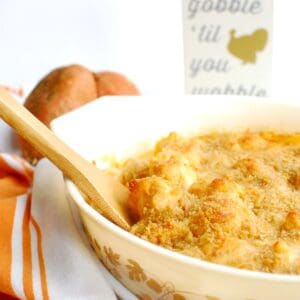 Sweetpotato cauliflower gratin in a casserole dish with a wooden spoon scooping out some.