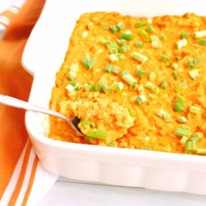 A spoon scooping vegetarian buffalo dip from a casserole dish.