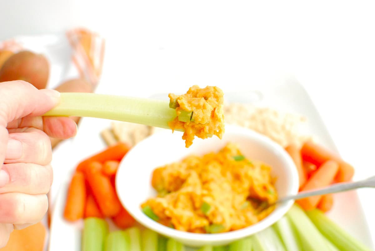 A piece of celery scooping up some buffalo dip.
