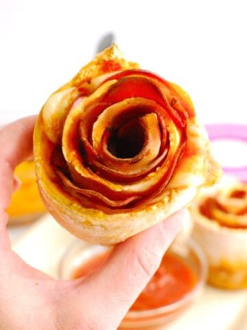 A woman's hand holding a pizza rose.