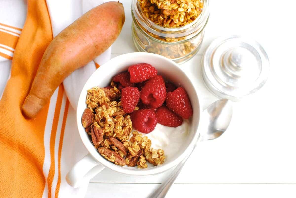 A bowl of yogurt with raspberries and sweetpotato granola.