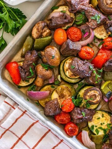 A sheet pan with cooked steak and veggies.