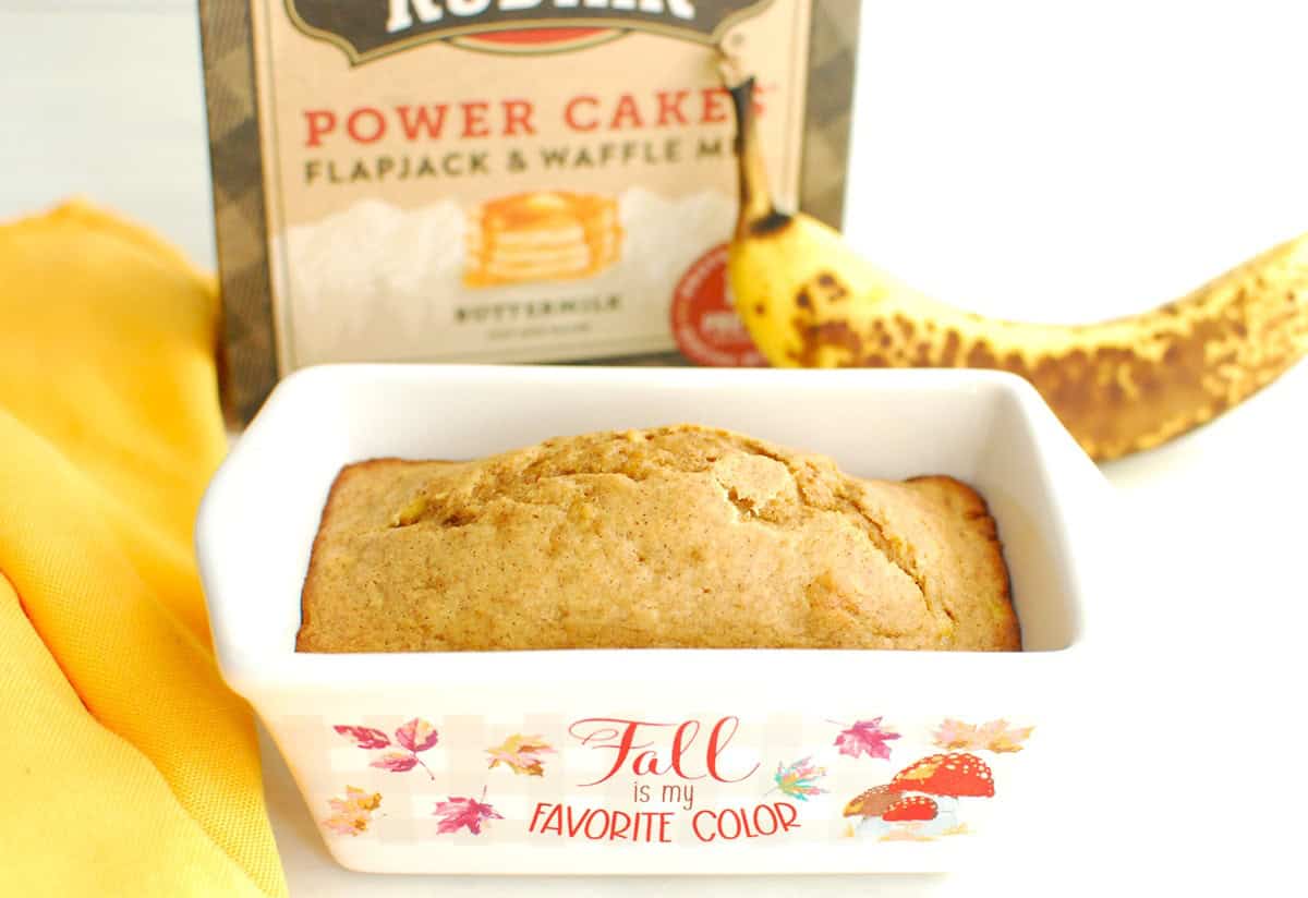 A mini banana bread made with just one banana, next to a napkin and banana.