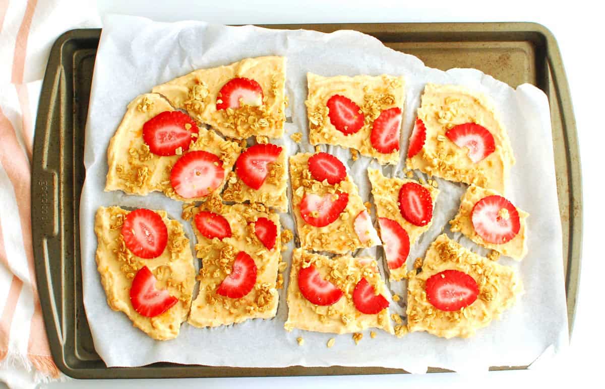 Frozen yogurt bark broken into pieces on a baking sheet.