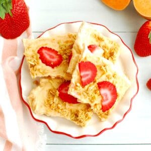 Greek yogurt bark topped with strawberries and granola on a plate.
