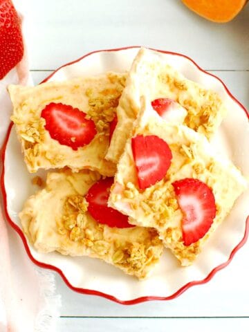 Greek yogurt bark topped with strawberries and granola on a plate.