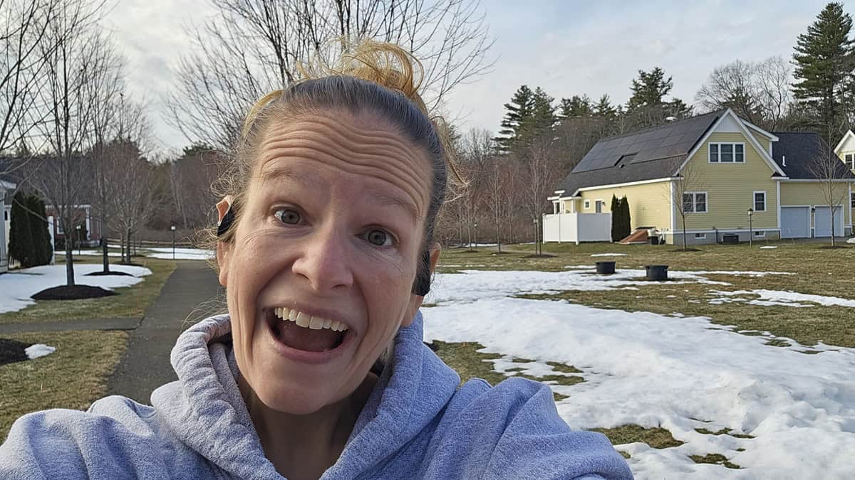 A woman smiling while outside exercising.
