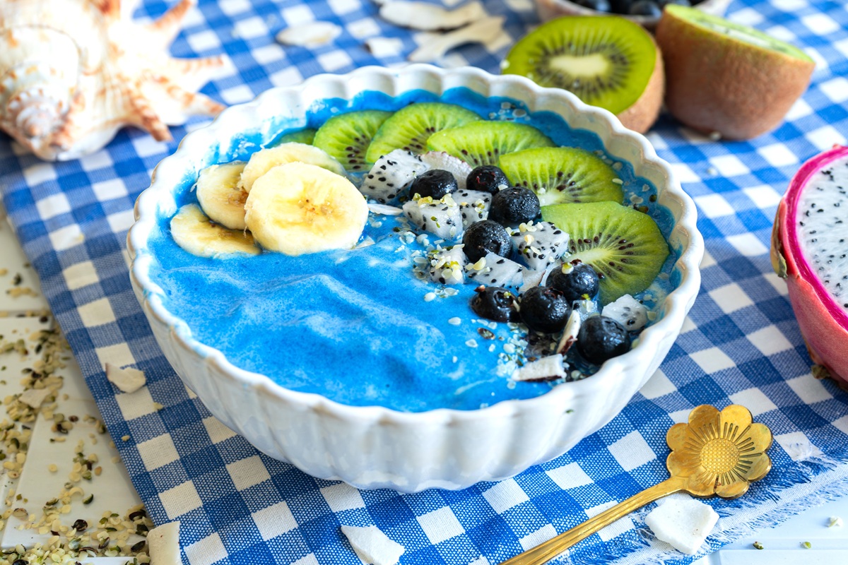 A blue mermaid smoothie bowl topped with banana, blueberries, dragonfruit, kiwi, and hemp hearts.