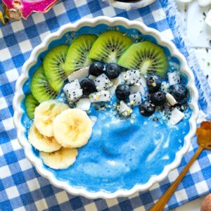 A blue mermaid smoothie bowl with toppings on a placemat.