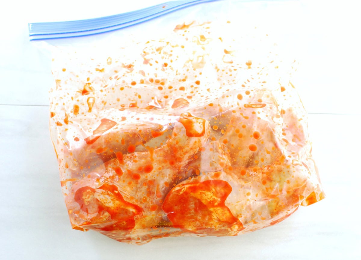 Chicken drumsticks in a large ziptop bag tossed with the marinade.