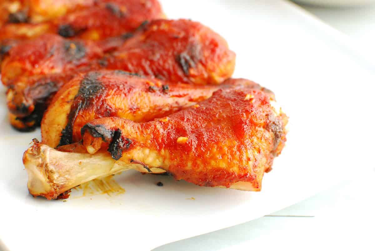 A close up of a gochujang chicken drumstick on a plate.