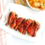 A bunch of gochujang chicken drumsticks on a white platter.