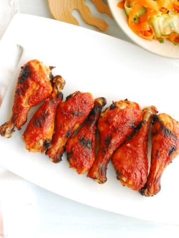 A bunch of gochujang chicken drumsticks on a white platter.