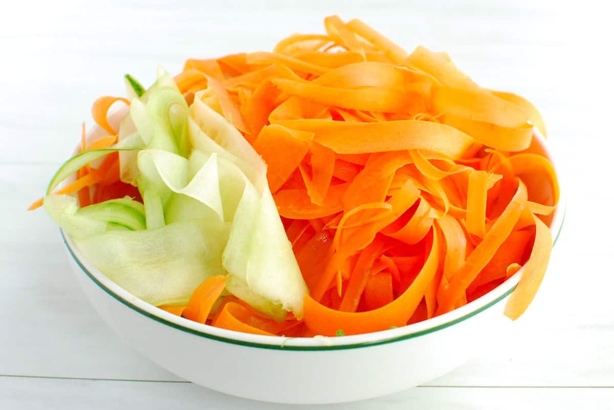 Cucumbers and carrots peeled into ribbons in a bowl.