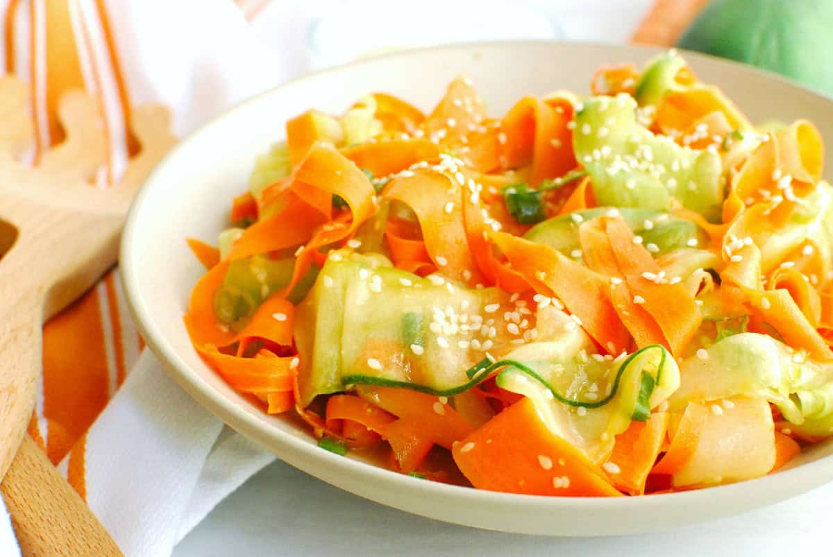 A close up of a bowl of sesame carrot cucumber salad.