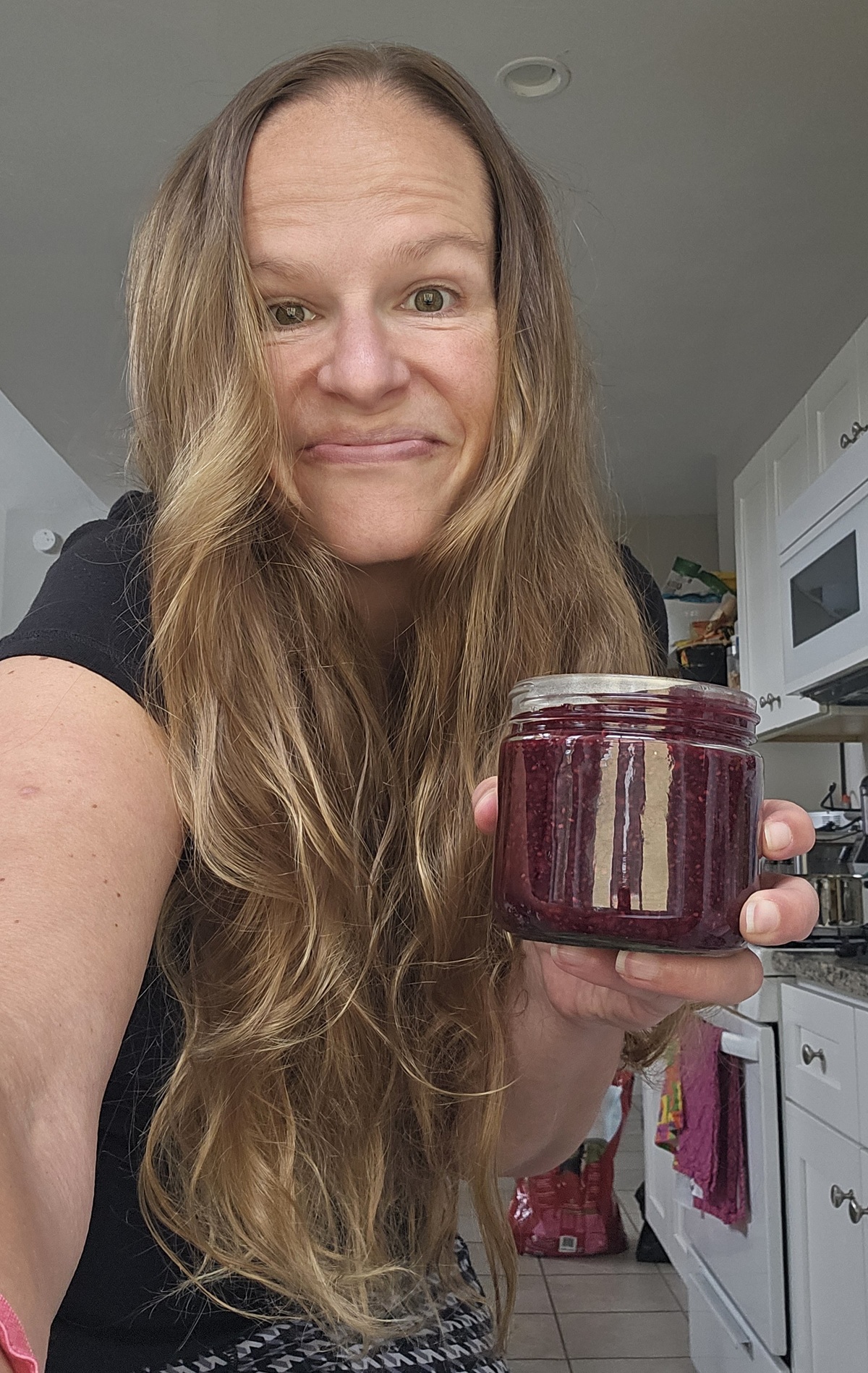 A woman holding a jar of chia jam.