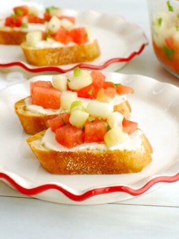 Two watermelon cucumber feta crostini on a plate.