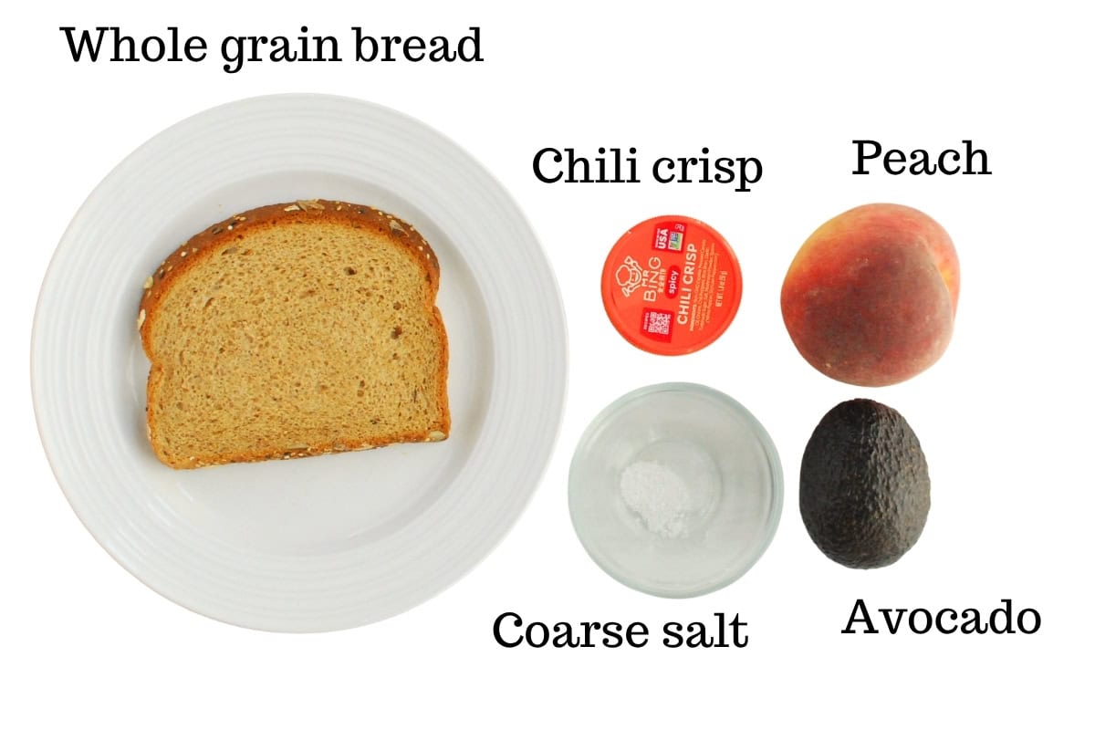 Bread, avocado, peach, chili crisp, and salt on a white background.