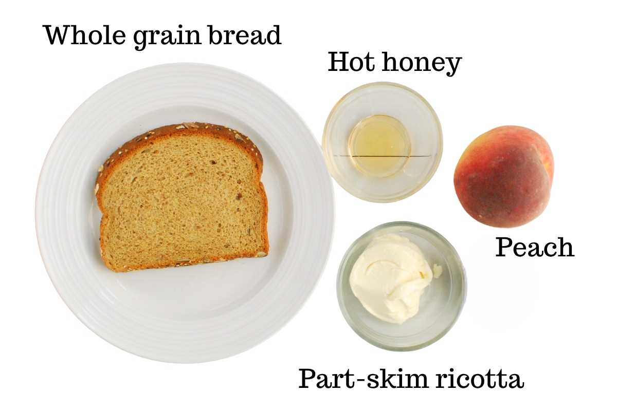 Whole grain bread, ricotta cheese, a peach, and hot honey, on a white backdrop.