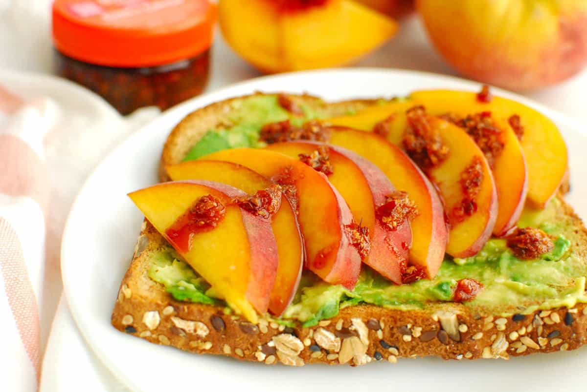 A close up of chili crisp on top of peach avocado toast.