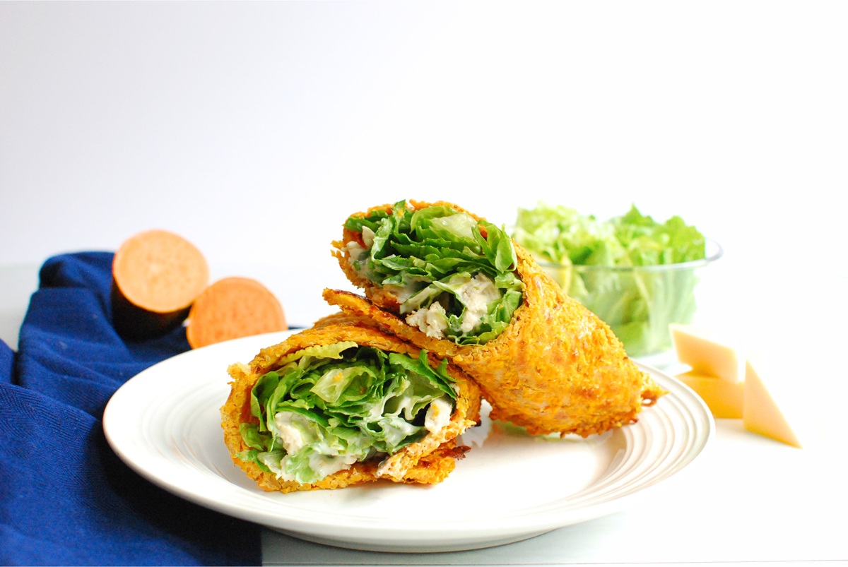 A sweetpotato wrap filled with chicken caesar salad on a plate.