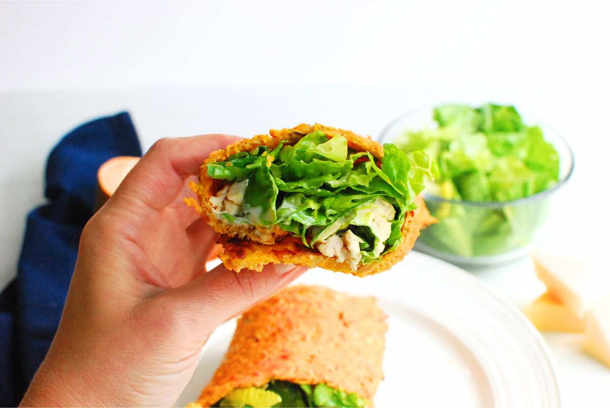 A hand holding the chicken caesar sweetpotato wrap.