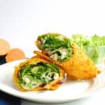 A chicken caesar salad sweetpotato wrap cut in half on a plate.