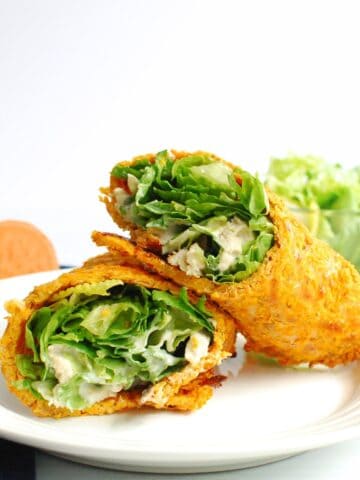 A chicken caesar salad sweetpotato wrap cut in half on a plate.