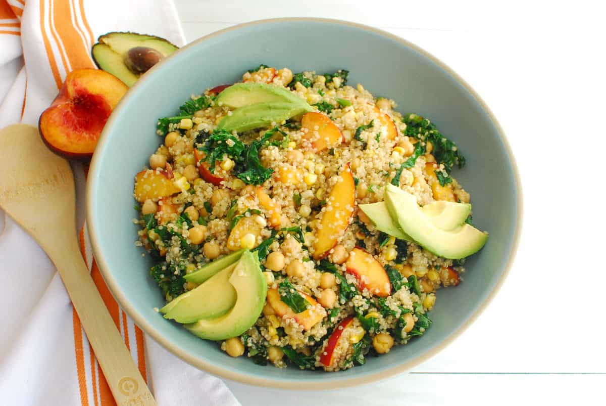 A bowl of peach quinoa salad garnished with avocado.