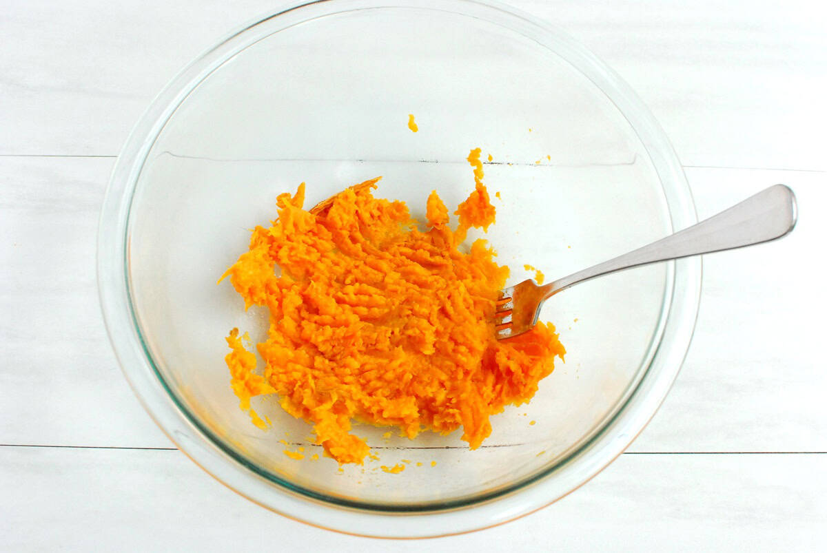 Mashed sweetpotato in a glass mixing bowl.