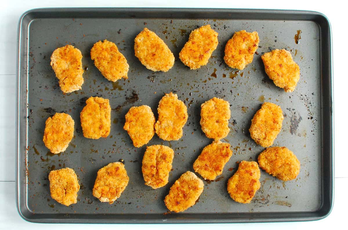 Baked chicken nuggets on a baking sheet.