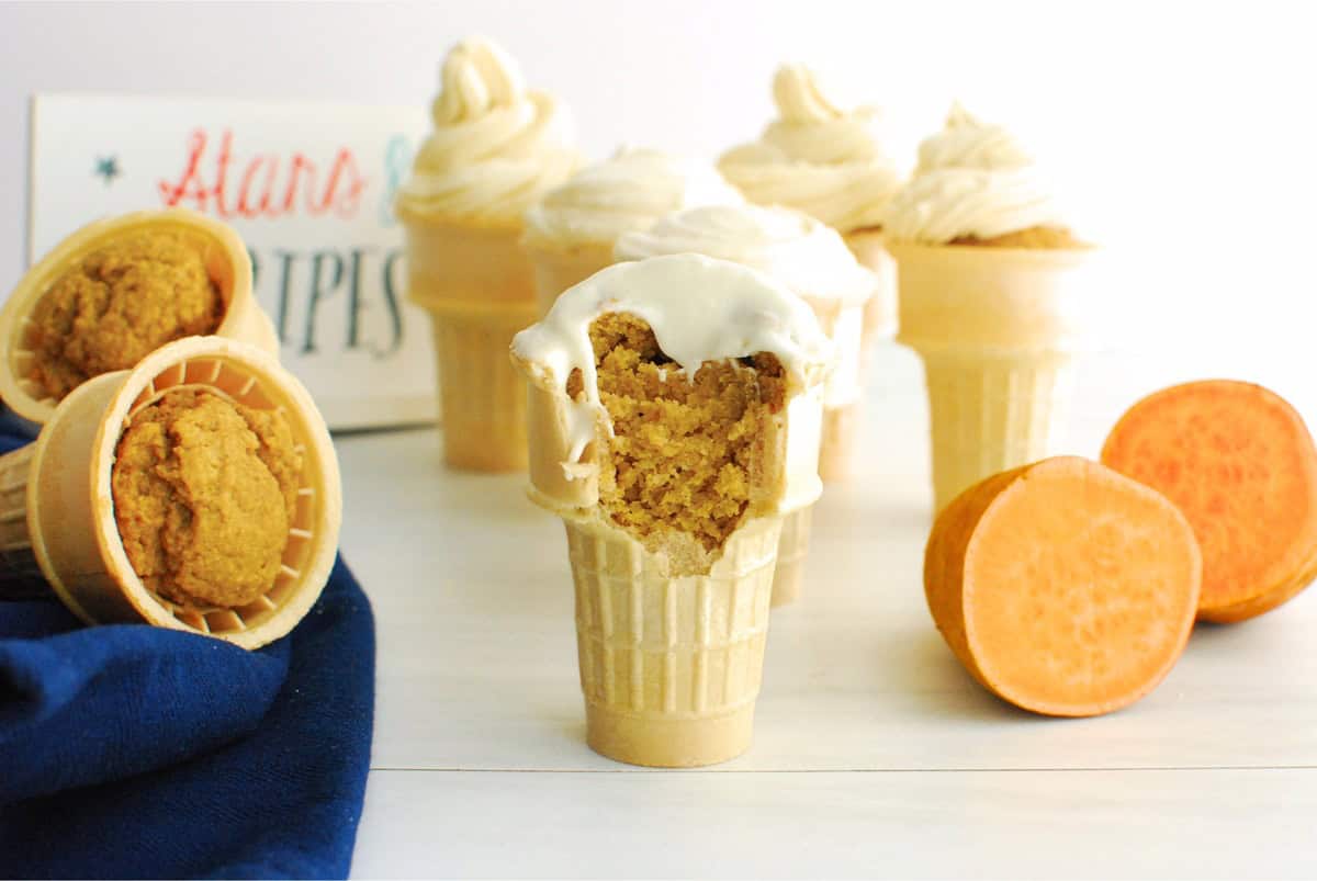 A bite taken out of a sweetpotato cupcake in an ice cream cone.
