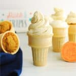 A sweetpotato cupcake in an ice cream cone with swirly frosting on top.