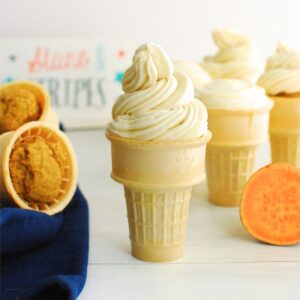 A sweetpotato cupcake in an ice cream cone with swirly frosting on top.