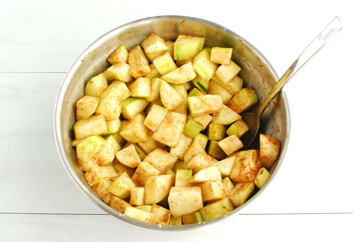 Zucchini in a bowl mixed with maple syrup, corn starch, lemon juice, cinnamon, and nutmeg.