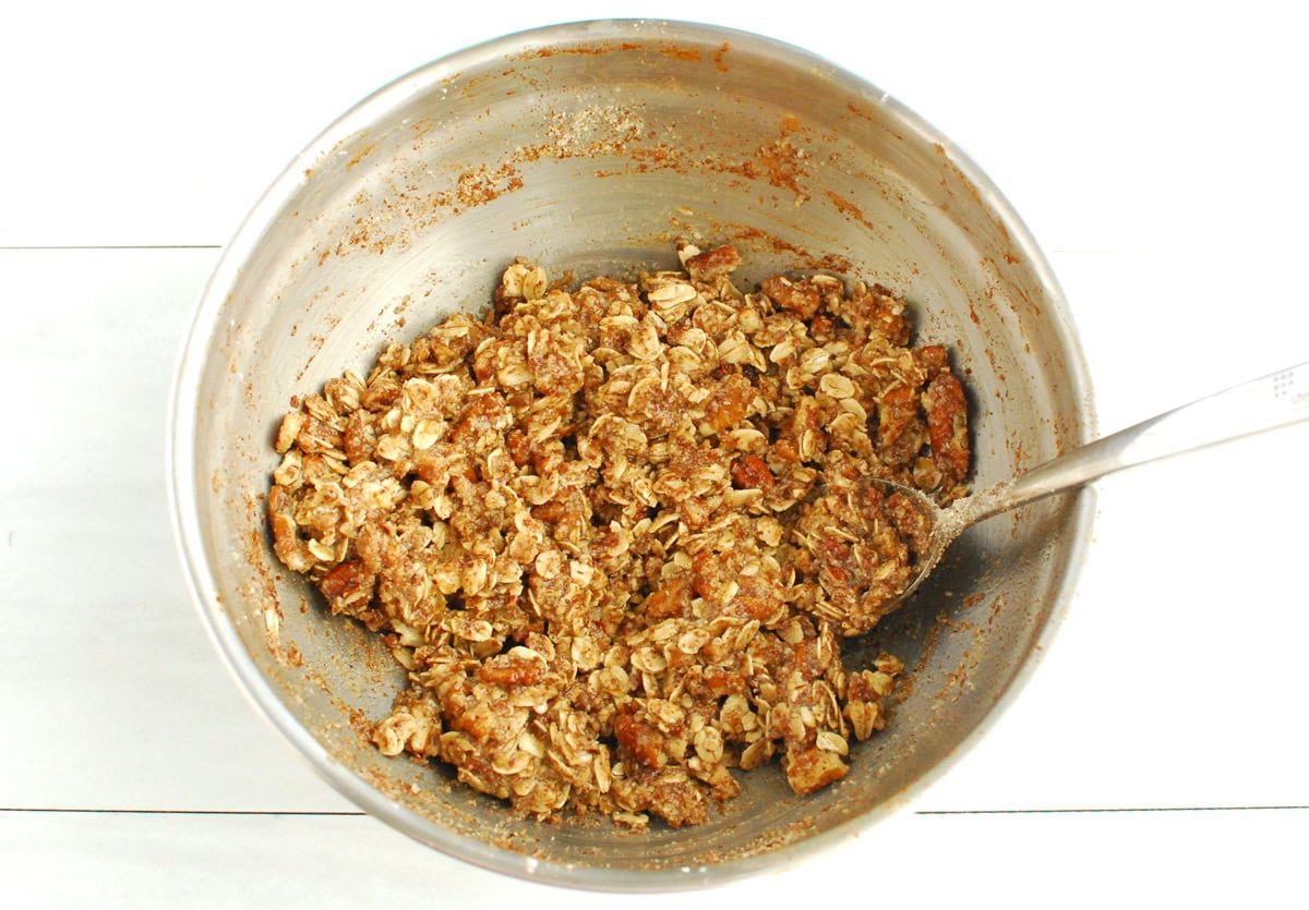 Oats, almond flour, pecans, cinnamon, salt, butter, and maple syrup mixed together in a bowl.